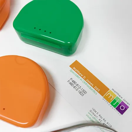 Multicolored retainer boxes beside the Matthew Jones Orthodontics business card